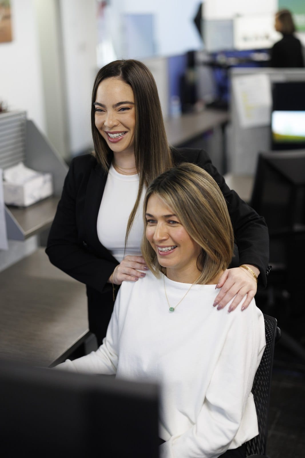Two members of the Elliott Insurance team laughing together at their desks